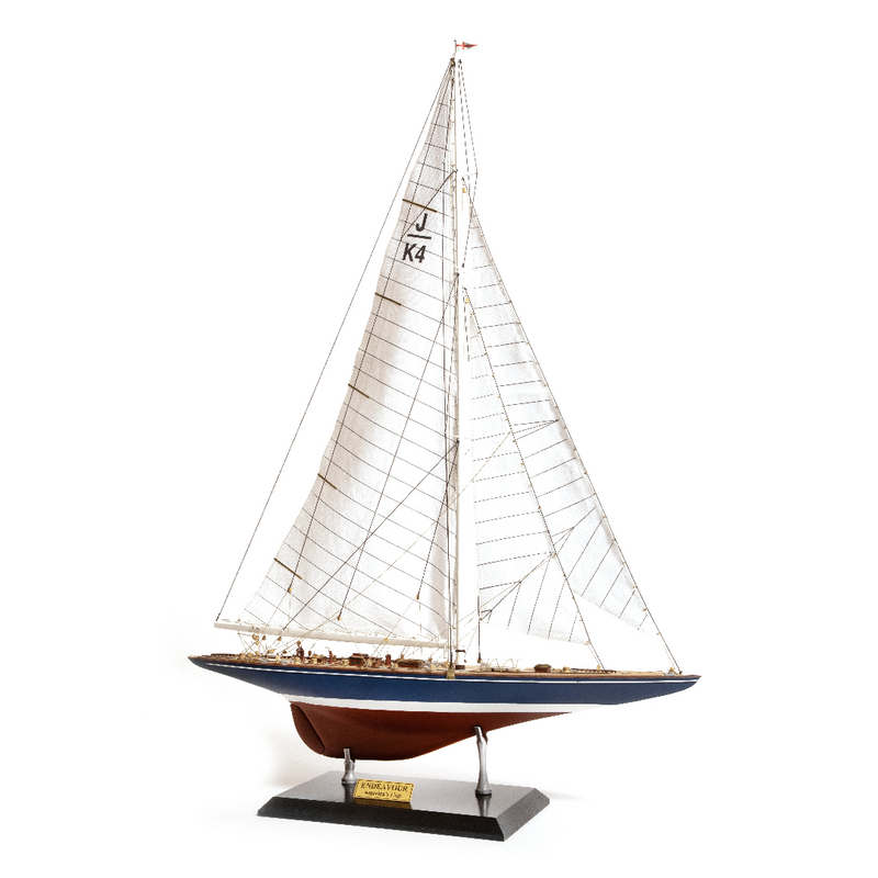 Photo of the OcCre Endeavour America's Cup yacht model kit in 1:75 scale, showing detailed wooden hull, rigging, and classic sail design.