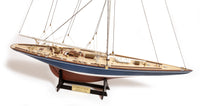 Photo of the OcCre Endeavour America's Cup yacht model kit in 1:75 scale, showing detailed wooden hull, rigging, and classic sail design.