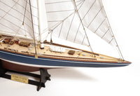 Photo of the OcCre Endeavour America's Cup yacht model kit in 1:75 scale, showing detailed wooden hull, rigging, and classic sail design.