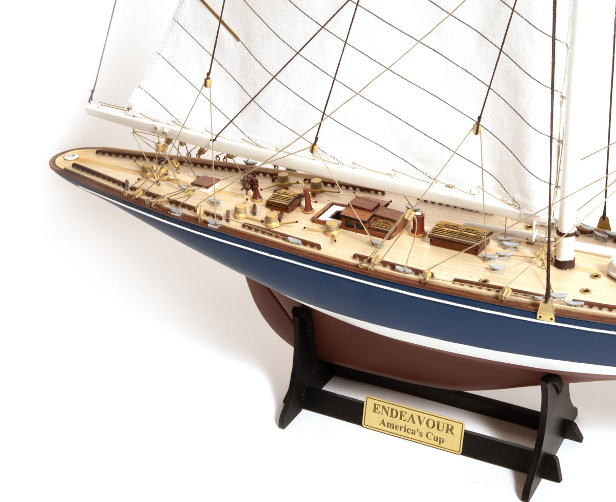 Photo of the OcCre Endeavour America's Cup yacht model kit in 1:75 scale, showing detailed wooden hull, rigging, and classic sail design.