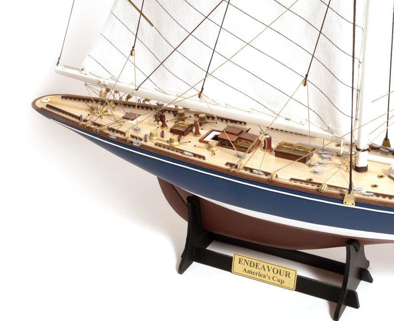 Photo of the OcCre Endeavour America's Cup yacht model kit in 1:75 scale, showing detailed wooden hull, rigging, and classic sail design.