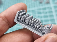 Set of small gray figurines held in a hand with a green cutting mat background