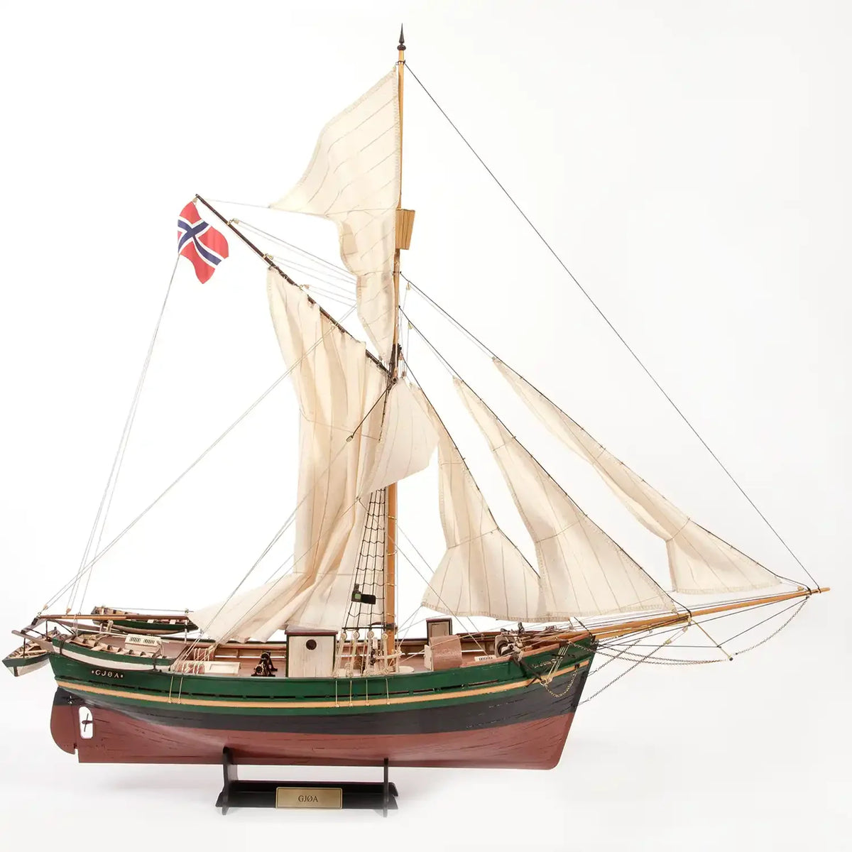 A detailed model of a historical Norwegian sailing ship with cream-colored sails, a green and brown hull, and a small Norwegian flag, displayed on a stand against a plain light background.