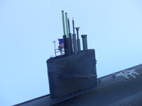 Model of a submarine with antennas and an American flag against a clear blue sky