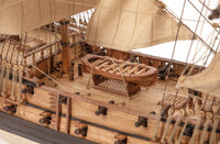 Close-up of a wooden model ship with detailed deck and sails.