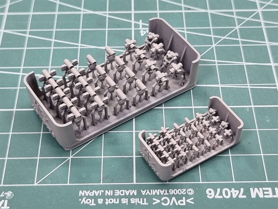 Set of small gray figures in a plastic tray on a green cutting mat.