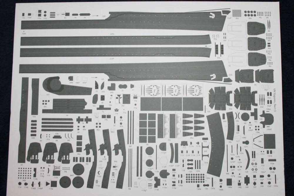 A sheet of model kit decals or cutaway parts laid out on a white backing, photographed from above against a dark background.