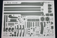 A sheet of model kit decals or cutaway parts laid out on a white backing, photographed from above against a dark background.