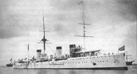 Black and white historical photograph of a large ocean liner or warship at sea, with masts, smokestacks, deck details, and flags visible against an overcast sky.