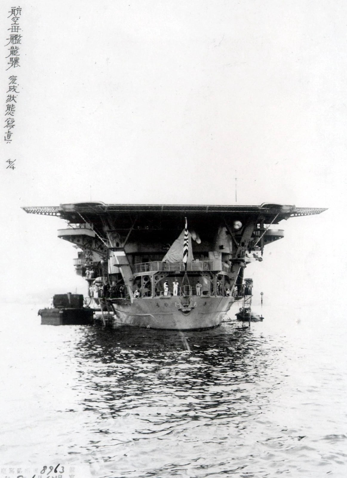 Black and white historical photograph of a large military aircraft carrier at sea, with Chinese characters printed along the left margin.