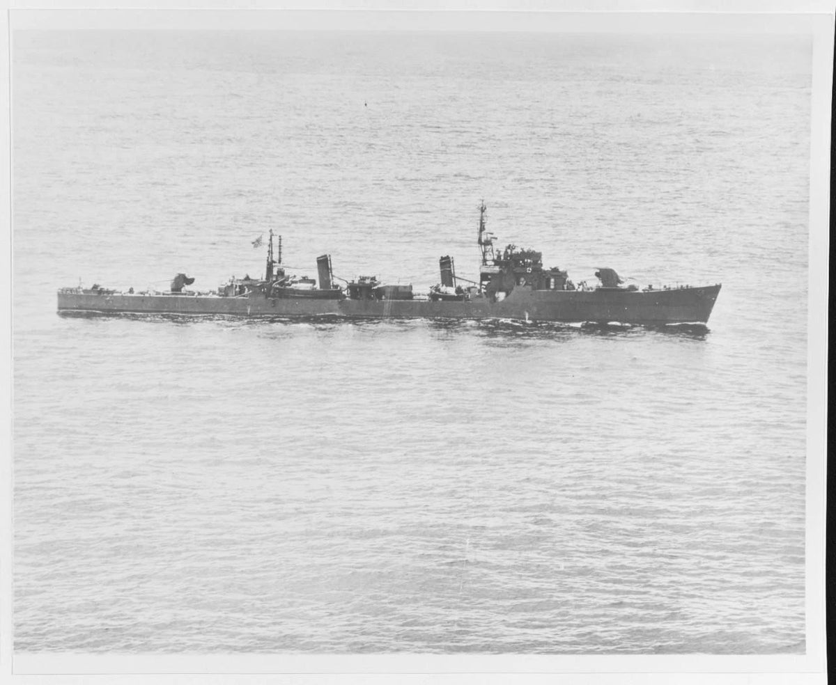 A black and white photograph of a military ship sailing on open water.