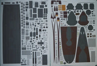 A sheet of model kit decals or transfer stickers laid flat on a white background, featuring various shapes, logos, and graphic elements in dark gray, black, brown, and small orange accents.