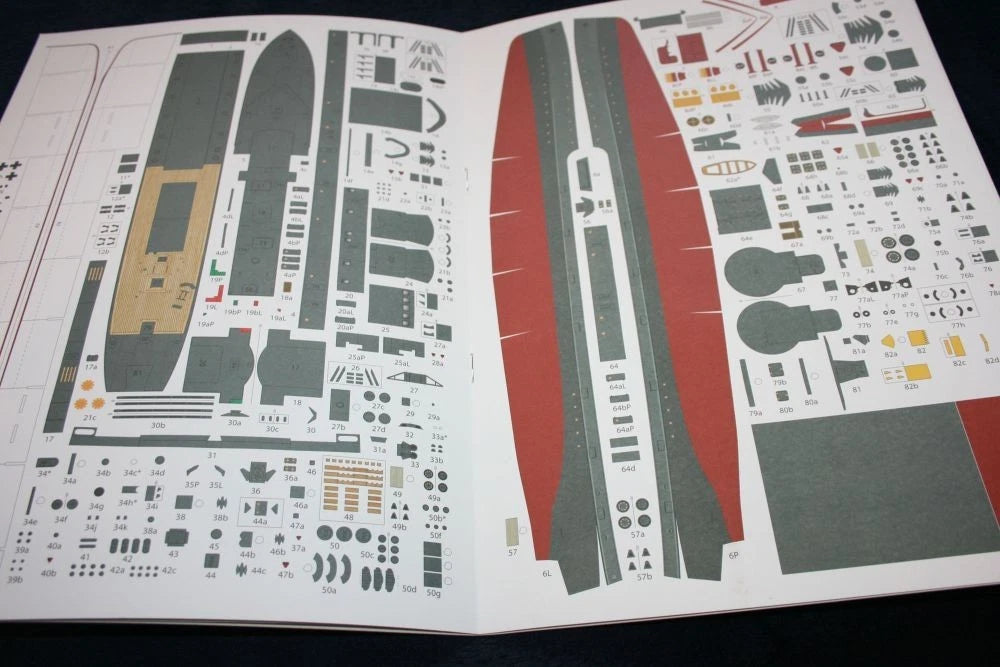 An open booklet or sheet containing many small printed decals or parts laid out on white paper, photographed from above against a dark background.