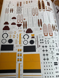 A printed decal sheet for a model boat, featuring various brown, black, and yellow cut-out pieces and markings on a white background.