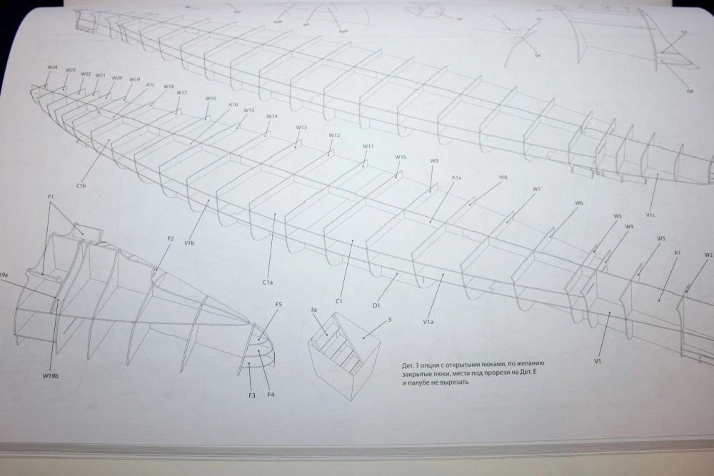 A close-up of a printed technical diagram or instruction sheet showing a long boat or hull outline with labeled parts and small text, photographed on a white background.