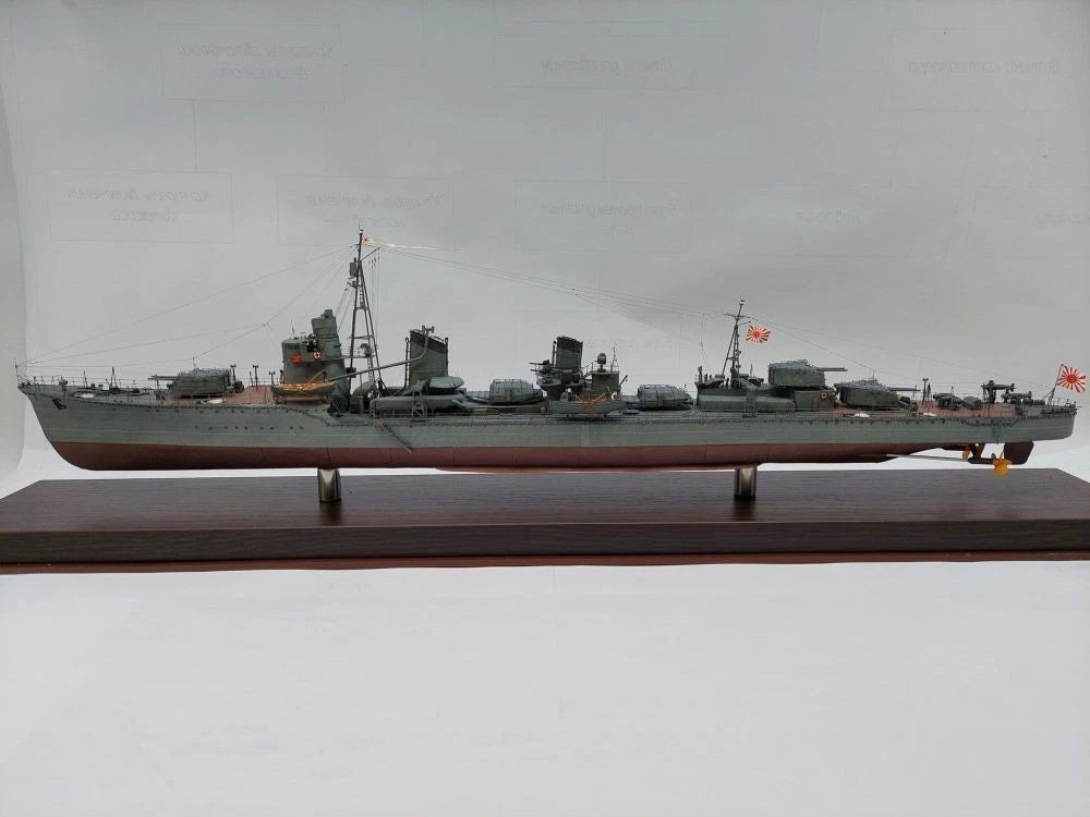 A detailed model of a Japanese military ship displayed on a dark wooden base against a plain light gray background.