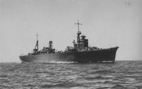 Black and white historical photograph of a military cargo ship sailing on open water under a pale sky.