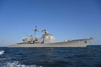 A gray military ship with the number 60 on its hull, sailing on blue ocean waters under a clear blue sky.