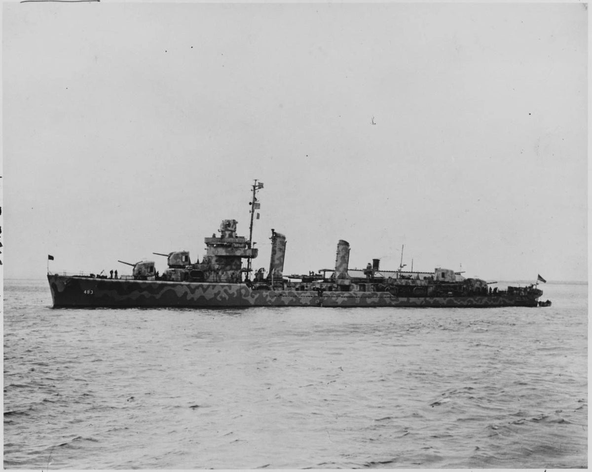 Black and white historical photograph of a military ship at sea, showing the vessel in profile against a flat sky and ocean surface.