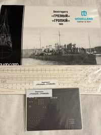 Model kit packaging and accessories for a Modelland Father & Son Destroyers 'Grozny' model ship, including a printed cover with a black-and-white historical photo, scale templates, and a metal sheet.