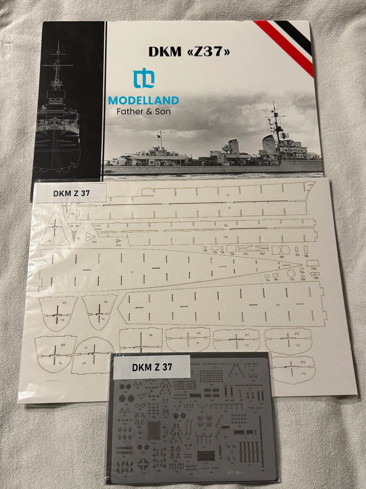 Model kit parts sheet and decal sheet for DKM Z37 model ship from Modelland, shown on a white fabric background.